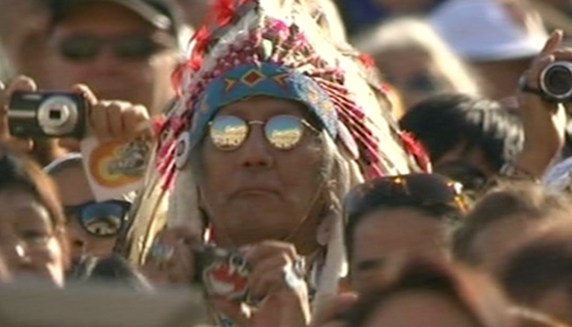 Native American taking photos during Canonization ceremony of Kateri Tekawitha. Freeze frame of Vatican TV video.