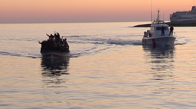 A boat of immigrants being escorted by the Coast Guard into the port of Lampedusa.  Freeze frame of video shot by AP cameraman Paolo Lucariello April 4, 2011