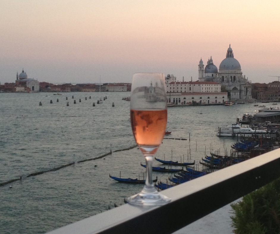 A glass of pink champagne perched on the railing of the Danieli Hotel Roof Terrace in Venice. August 31, 2013. Photo by Trisha Thomas