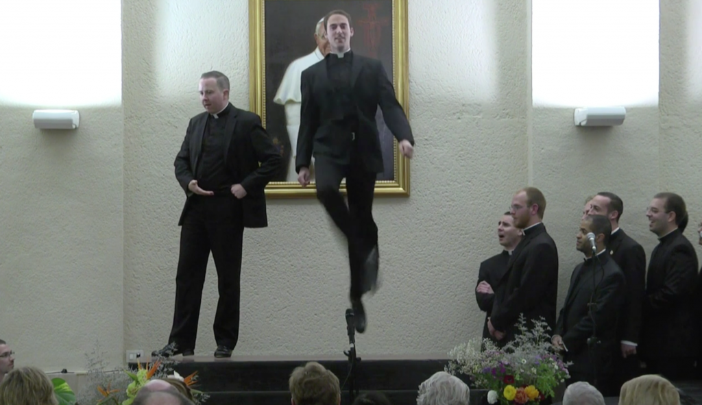 Father John Gibson jumping high in an Irish dance routine at the North American College performance. April 29, 2014. Freeze frame of Video. Credit: Pontifical North American College and Mr. J William Sumner