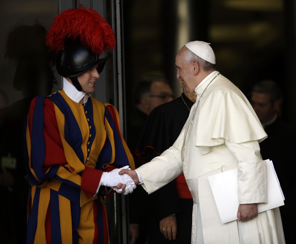 Pope Francis stops and shakes hands with a Swiss Guard as he enters into the Synod Hall for the Extraordinary Synod on the Family.  October 2014. Photo by AP Photographer Gregorio Borgia for Mozzarella Mamma