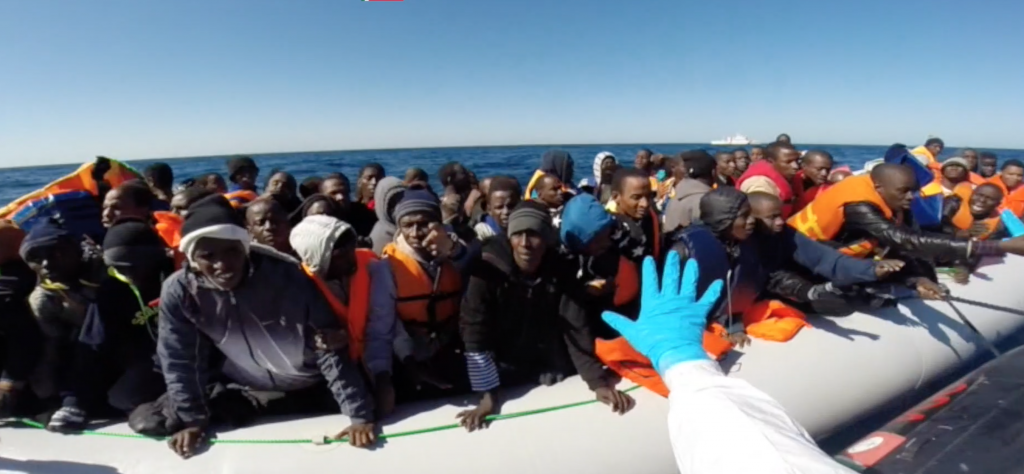 Italian Coast Guard rescuing migrants coming on a rubber dinghy from Libya on February 17, 2015. Freeze frame of video provided by Italian Coast Guard