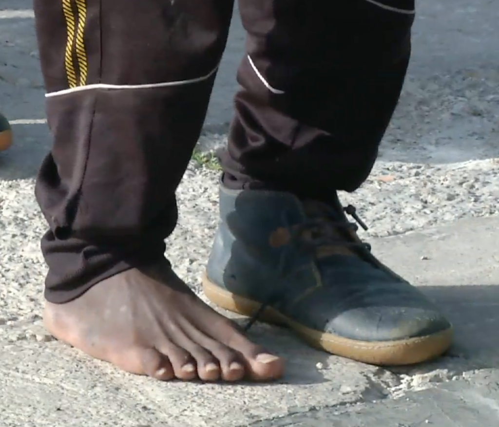 A migrant rescued at sea disembarks from a Coast Guard ship in the Italian port of Pozzallo with one shoe and one bare foot. April 17, 2015. Freeze frame of video shot by AP Television Cameraman Luigi Navarra
