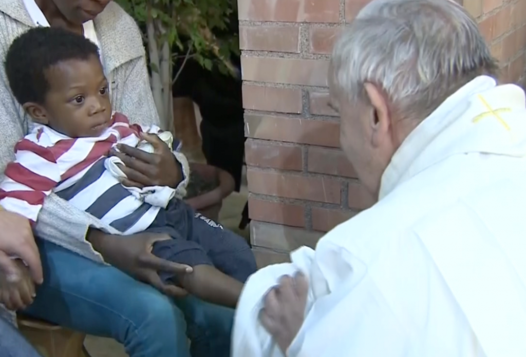 Pope washing the feet of a little boy in the lap of his mother, a prison inmate in Rome, as part of the Holy Thursday foot-washing Mass at the Rebibbia Prison in Rome. April 2, 2015. Freeze frame of video released by Vatican TV.