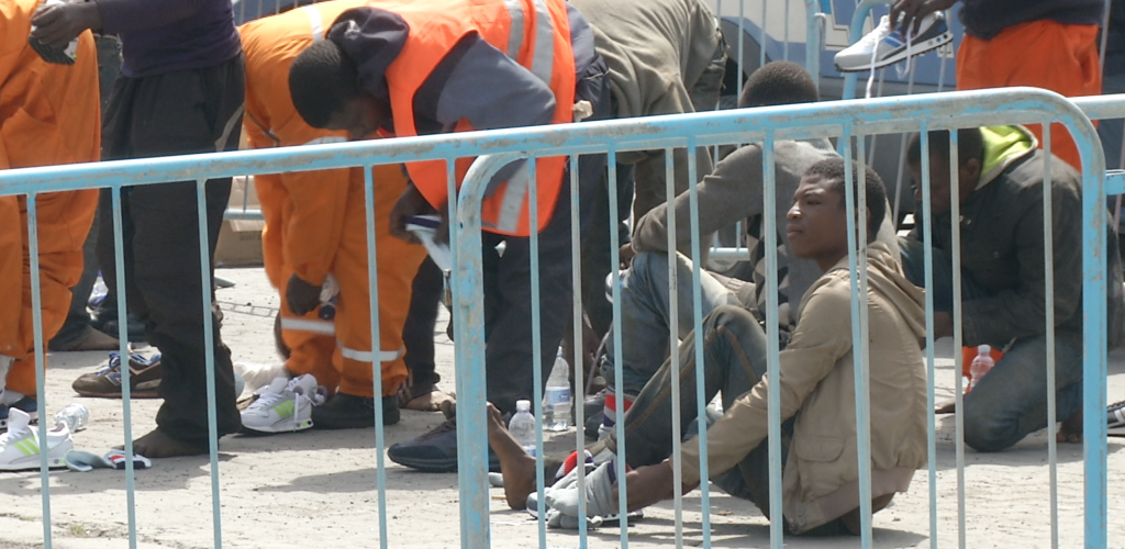 Migrants putting on new sneakers on dock in port of Catania. May 5, 2015. Freeze frame of video shot by AP Television Cameraman Andrea Rosa