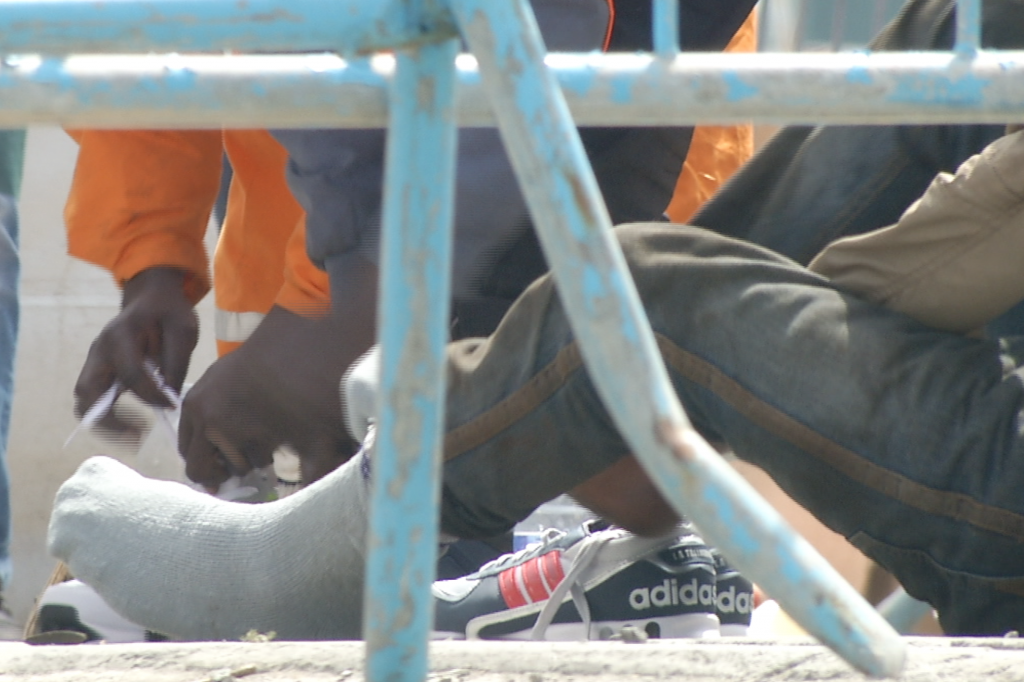 Migrant putting on his new counterfeit Adidas in port of Catania, Sicily. May 5, 2015. Freeze Frame of video shot by AP video-journalist Andrea Rosa
