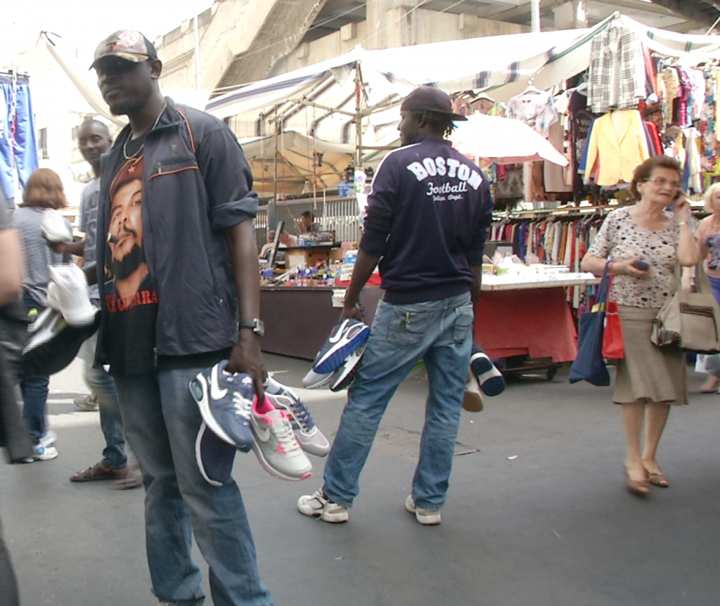 Senagalese men selling counterfeit sneakers in the main market in Catania. May 7, 2015. Freeze frame of video shot by AP video-journalist Andrea Rosa