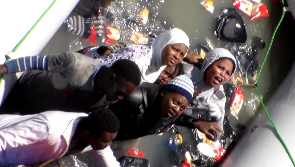 Mothers with children yell at sailors on board merchant ship Zeran asking for help as their deflating dinghy is filling up with water.  Freeze frame of video shot by Polish seaman. May, 2015 (video copy right of AP see www.aparchive.com )