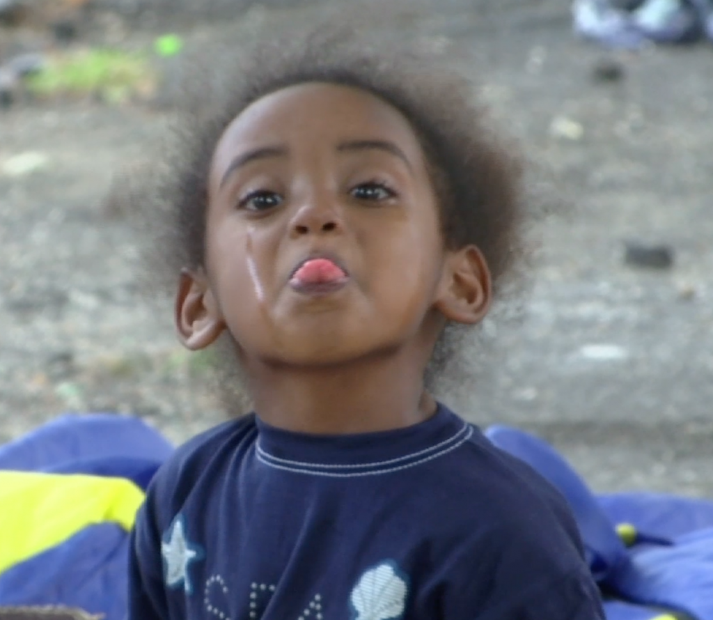 Little migrant girl sitting on ground at Tiburtina bus terminal in Rome. June 11, 2015.     Freeze frame of video shot by AP Television cameraman Luigi Navarra.