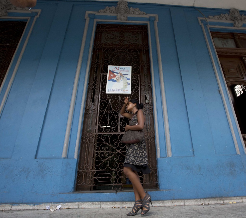 Cuban woman walks past sign welcoming Pope Francis on a door in Havana, Cuba. September 18, 2015. Photo by AP photographer Alessandra Tarantino for Mozzarella Mamma
