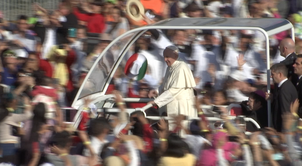 A woman waves a tri-color Mexican hat as Pope Francis arrives at the Basilica of Our Lady of Gaudalupe. Freeze frame of video by AP VJ Paolo Santalucia. February 13, 2016