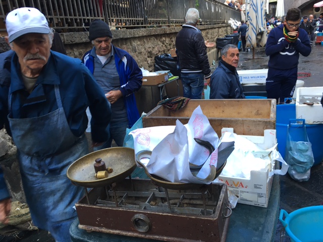 Man selling live eels which he weighs on a bronze scale in Catania's "La Pescheria" fish market. Photo by Trisha Thomas, November 12, 2016