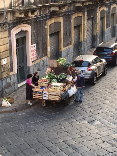 Women in their bedroom slippers having a good chat with the fruit and vegetable seller on a street in Catania. Photo by Trisha Thomas, October 6, 2016