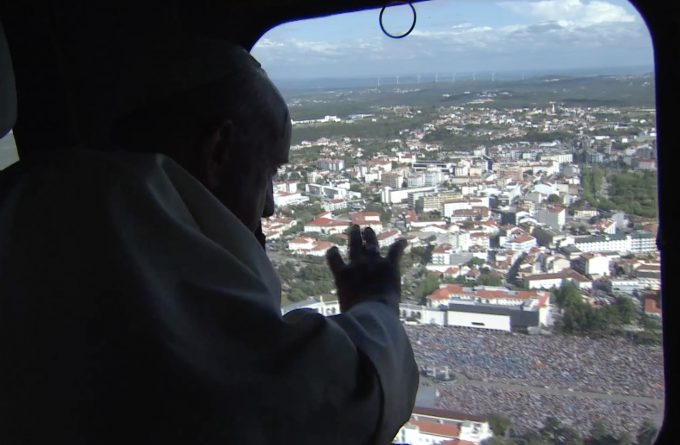 Pope Francis waves from the window of a Portuguese military helicopter as it circles above the hundreds of thousands of people gathered at the Sanctuary of Our Lady of Fatima. Freeze frame of video shot by Vatican TV. May 12, 2017.