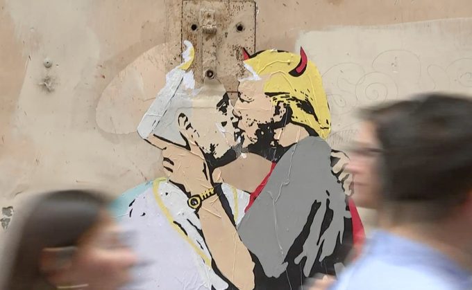 A mural on a small street near the Vatican showing Donald Trump dressed as the devil kissing Pope Francis with a Halo. Freeze Frame of Video shot by Cameraman Paolo Lucariello for AP Television. May 12, 2017